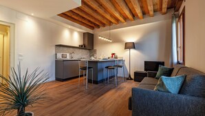 Une cuisine moderne avec un coin bar, des poutres en bois au plafond, un canapé et un lampadaire.