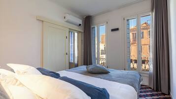 Una habitación de hotel con una cama, una ventana con cortinas y un equipo de aire acondicionado.