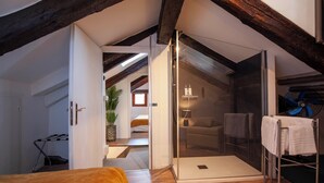 Une chambre moderne avec un plafond en bois, une cabine de douche en verre et un lit doté d’une tête de lit jaune.