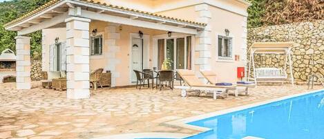 A two-story building with a pool, stone flooring, and outdoor seating.