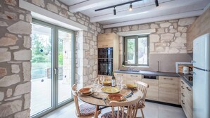 Een moderne keuken met stenen muren, een eethoek met een ronde tafel en stoelen, en een inbouwoven.