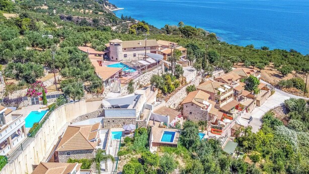 Zona residencial a la costa amb diverses cases, una piscina i vistes al mar.