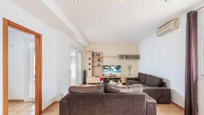 A modern living room with a sofa, TV, and a bookshelf.
