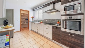 A modern kitchen with stainless steel appliances, wooden cabinets, and a tiled floor.