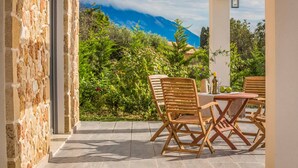 Un patio al aire libre con una mesa y sillas, un muro de piedra y vistas a la montaña.