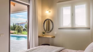 Un dormitorio con una cama, una mesita de noche con lámpara, un espejo y una ventana.