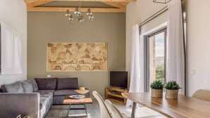 Un salón moderno con un sofá gris, una mesa de comedor de madera y un cuadro abstracto grande en la pared.