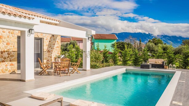 Un área de piscina moderna con muros de piedra, piscina y mobiliario exterior.