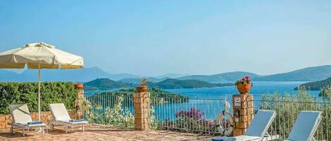 Relax by the pool surrounded by lounge chairs and a stunning view of the water and mountains.