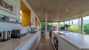 Une cuisine moderne dotée d’un long plan de travail, de meubles blancs et offrant une vue sur l’extérieur.