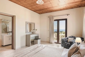 Ein Schlafzimmer mit Bett, Kommode, Spiegel, einem Fenster mit Vorhängen und einem Balkon mit Blick.