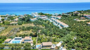 Un complejo turístico costero con villas, una piscina y vistas al mar.