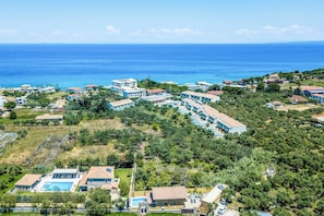 A coastal resort with villas, a swimming pool, and a view of the sea.