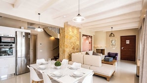 Una cocina moderna con un refrigerador de acero inoxidable, una mesa de comedor preparada para cuatro comensales y una escalera que lleva a un nivel superior.