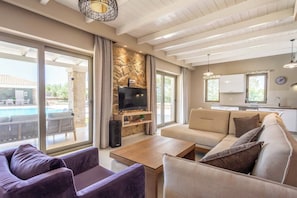 A living room with a sofa, a coffee table, a TV, and a stone wall.