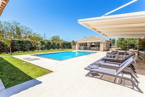 A poolside area with a pool, lounge chairs, and a covered patio.