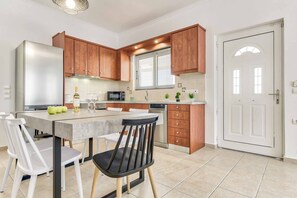 Eine moderne Küche mit Holzausbau, einem Edelstahlkühlschrank, einer Mikrowelle und einem Essbereich mit einem Marmortisch und Stühlen.