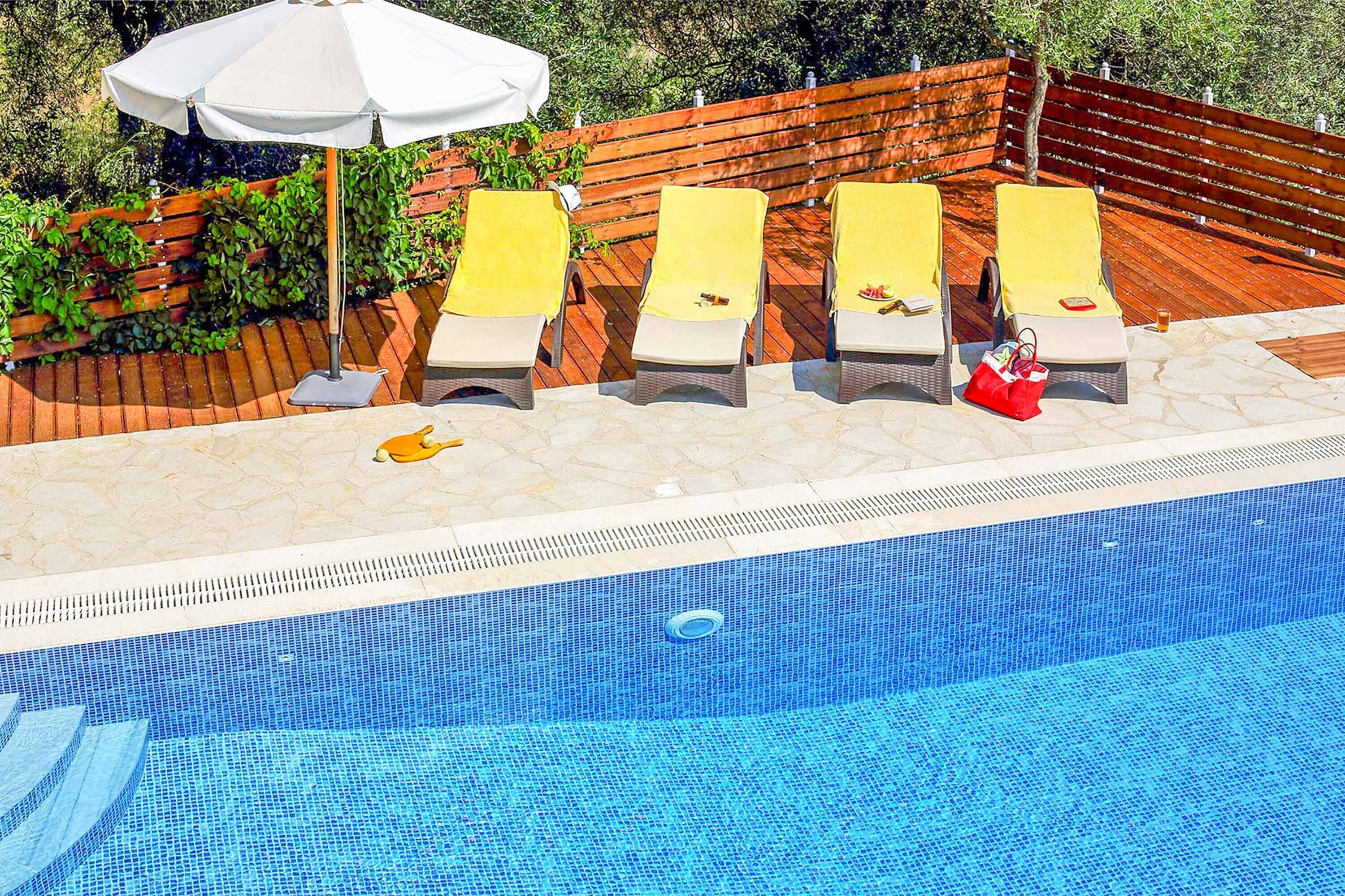 Una piscina con sillones de descanso y una sombrilla blanca.