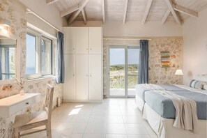 Ein Schlafzimmer mit Bett, Schreibtisch, Stuhl, Kleiderschrank und Blick ins Freie.
