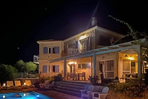 A two-story building with a pool, outdoor seating, and a covered patio area.