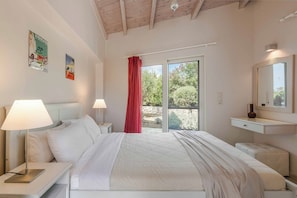 Ein Schlafzimmer mit Bett, Nachttischen, einem Spiegel und einem Fenster mit Blick auf Grünfläche.