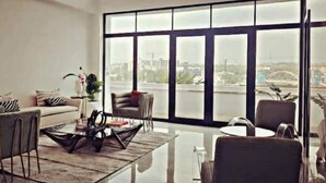 A modern living room with a large window, a sofa, a coffee table, and a chair.