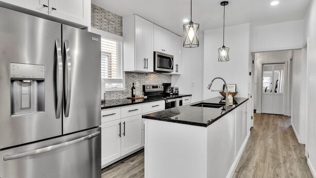 Una cocina moderna con electrodomésticos de acero inoxidable, armarios blancos y una isla central.
