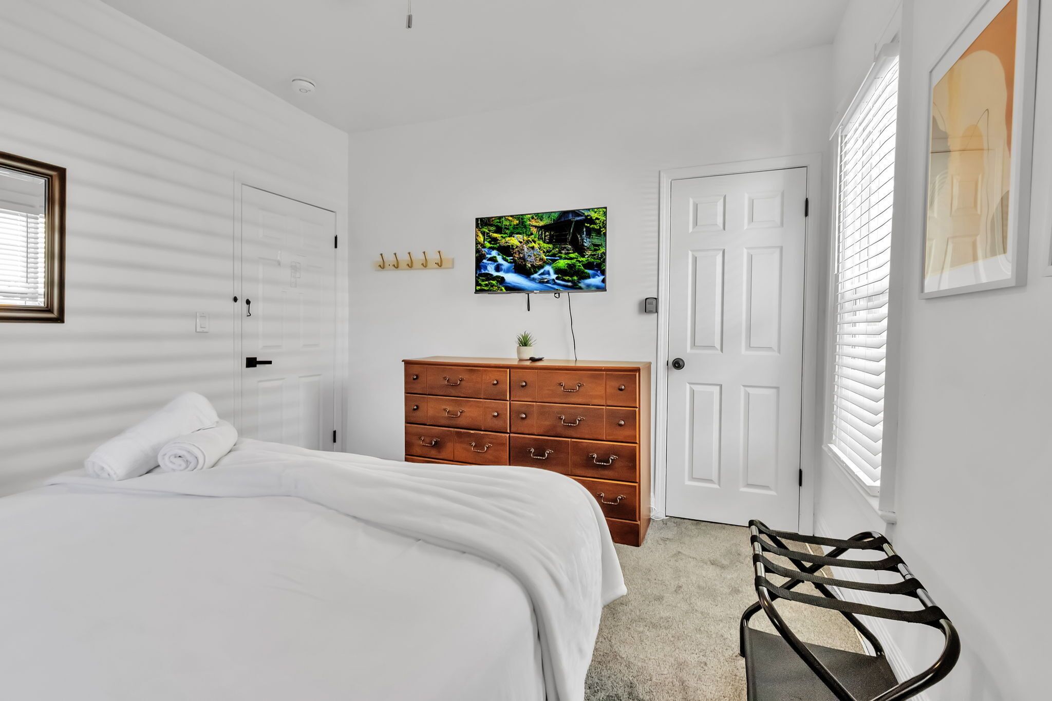 Een slaapkamer met een bed, een dressoir, een televisie en een stoel.