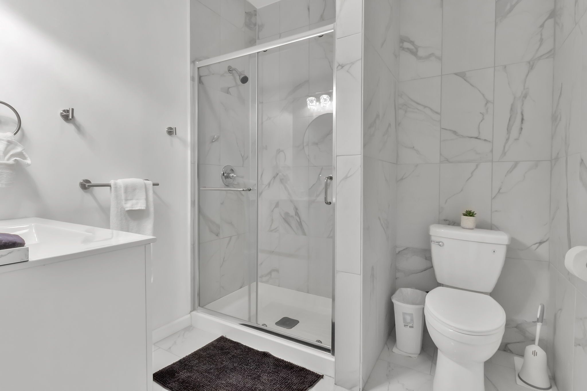 Un baño moderno con ducha acristalada, lavamanos blanco y un inodoro.