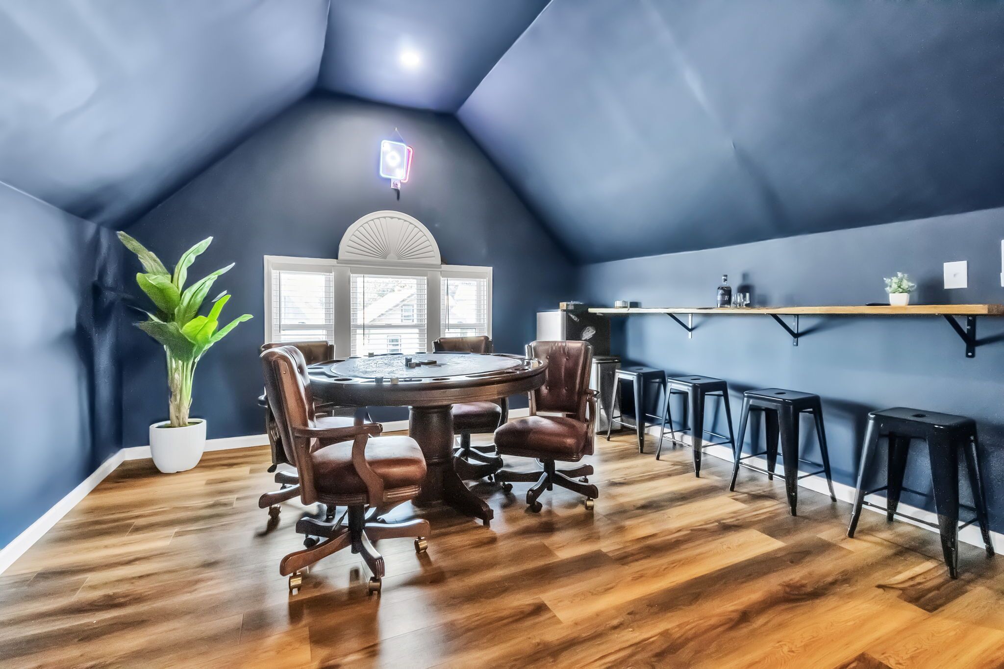 Une salle de conférence avec une table ronde, des fauteuils en cuir, une plante en pot et une fenêtre avec des stores.