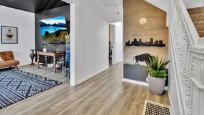 Un interior moderno con una escalera, un mural de paisaje urbano y vistas a un lago.