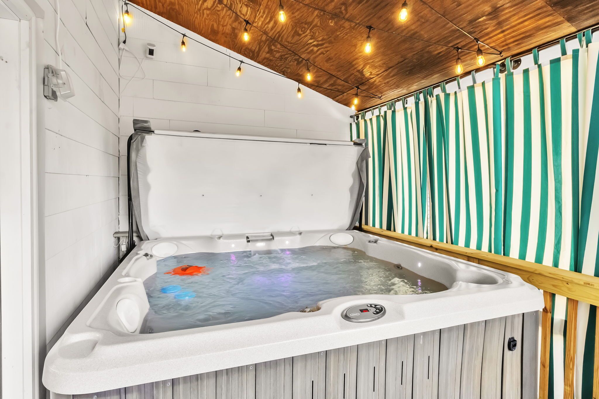 Un bain à remous avec un plafond en bois et des rideaux à rayures.