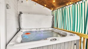 Un jacuzzi con techo de madera y cortinas a rayas.