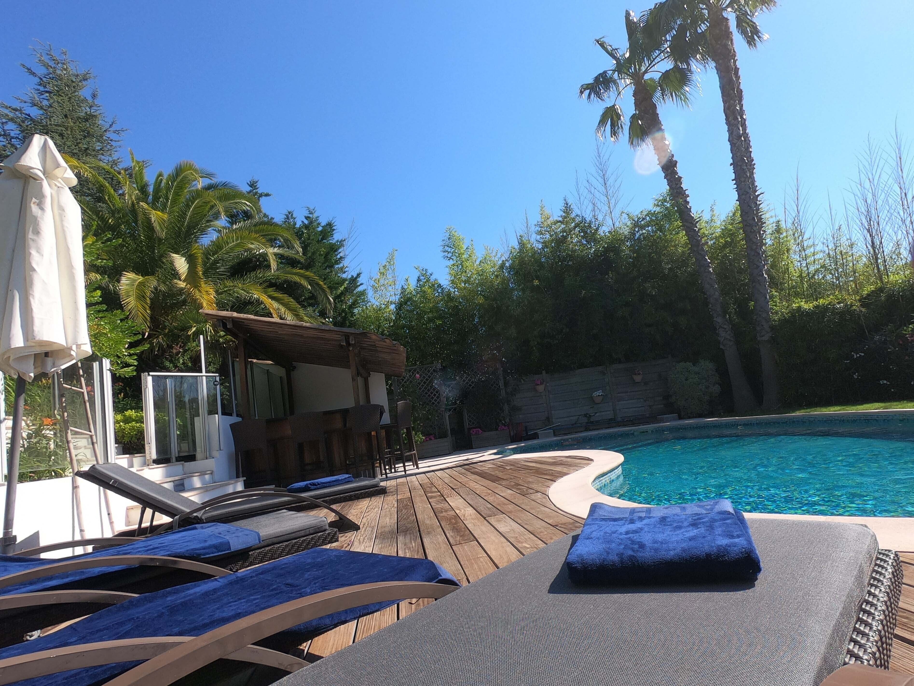 A wooden deck with lounge chairs and a pool.