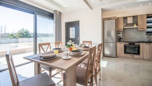 Een moderne keuken met roestvrijstalen apparatuur, een eetgedeelte met een houten tafel en stoelen, en een groot raam met uitzicht op de omgeving.