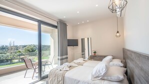 Een moderne hotelkamer met twee bedden, een balkon met een stoel en een televisie aan de muur.
