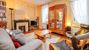 Un salon chaleureux avec une cheminée, un canapé, un fauteuil et une table basse en bois.
