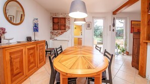 Un coin repas avec une table et des chaises en bois, un buffet en bois et un luminaire suspendu.