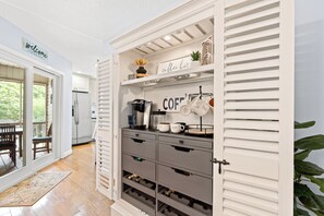 A kitchen with white cabinetry, a coffee station, and a wine rack.