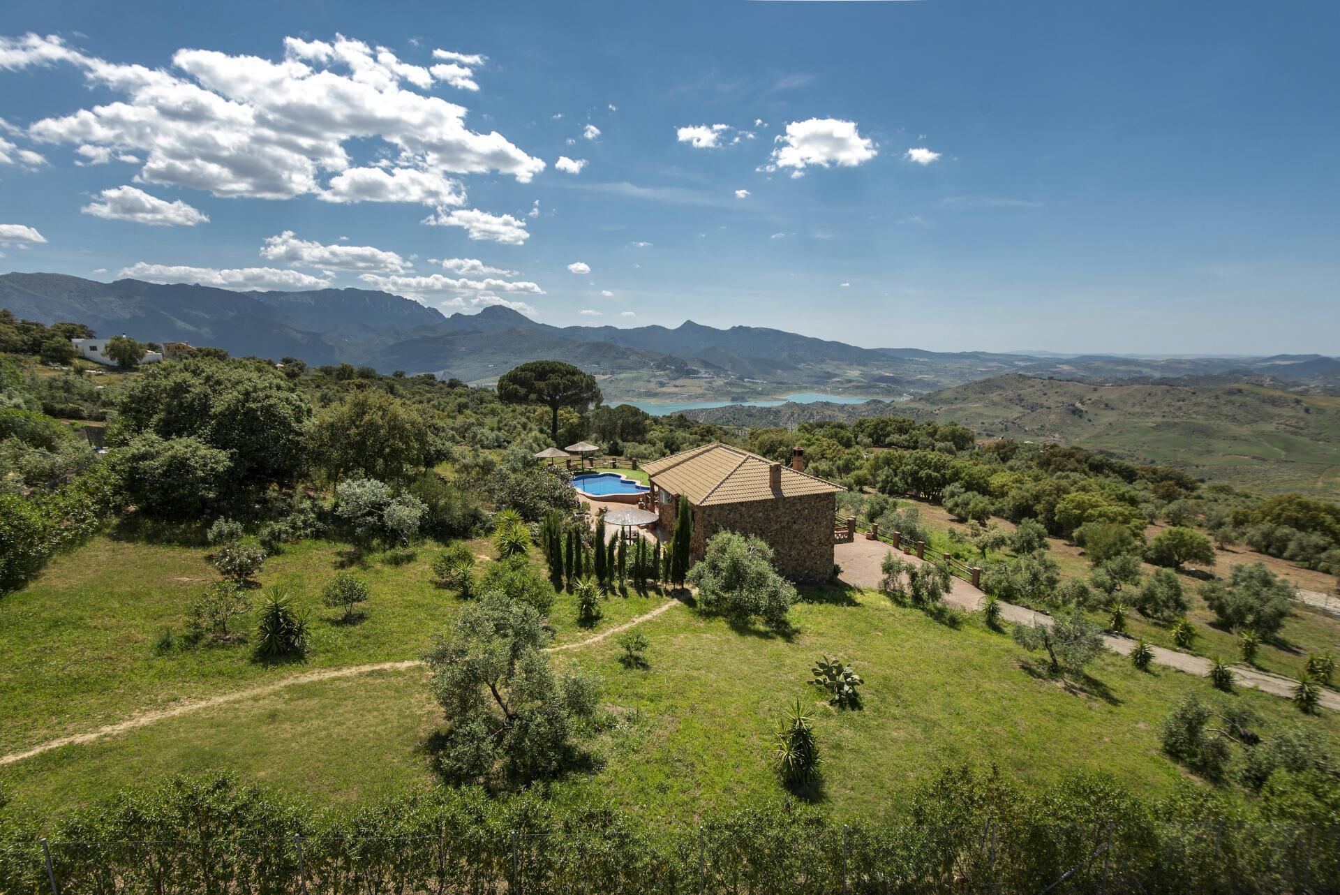 A villa with a swimming pool, surrounded by lush greenery and mountains in the background.