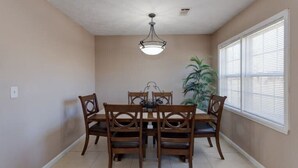 A dining room with a table and chairs, a ceiling light, and a window with blinds. - Harris County Ranch Hideaway (Hamilton)