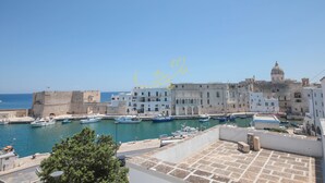 A coastal town with a historic fort, a harbor with boats, and buildings with balconies.