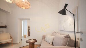A modern living room with a beige sofa, a round coffee table, a floor lamp, and a wall with abstract art.