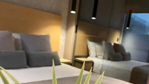 Une chambre d’hôtel moderne avec un grand lit, une table de chevet et un petit coin salon.