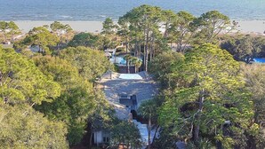A beachfront property with a swimming pool, surrounded by dense trees and overlooking the ocean. - Oceanfront Sea Pines Home w/ Pool (Hilton Head Island)
