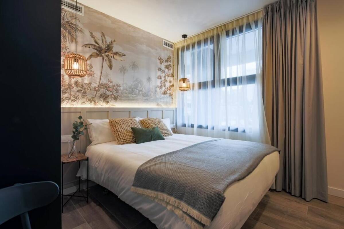 A bedroom with a bed, a nightstand, a lamp, and a wall mural.