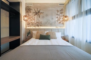 A neatly made bed with a patterned bedspread, two decorative pillows, and a headboard with a floral mural. - Home42 (Madrid)