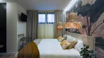 Una habitación de hotel con una cama, un televisor en la pared, una ventana con cortinas y un mural en la pared.