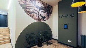 Un interior moderno con una pared curva, dos sillas negras, una planta en maceta y un letrero que dice 'HOME 42'.