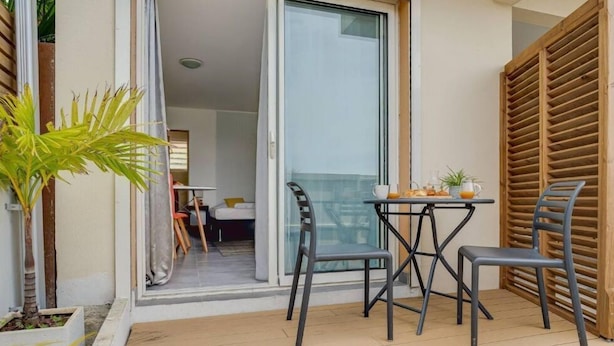 A balcony with a table and chairs, a sliding glass door, and a wooden fence. - Studio Centre Ville - Vue mer ! (Saint-Pierre)
